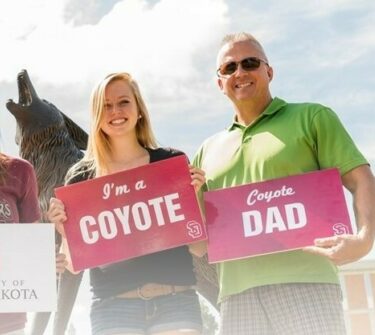 A family stands in front of the Legacy statue on campus.